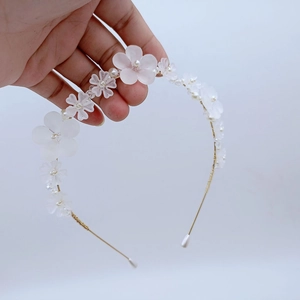 Détail d'un serre-tête en fil doré fait main avec fleurs blanches et perles