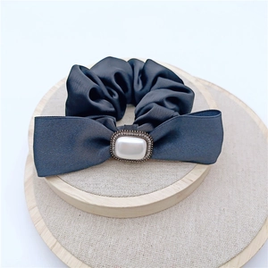 Détail d'un chouchou en satin bleu foncé avec perle nacrée et cristaux scintillants