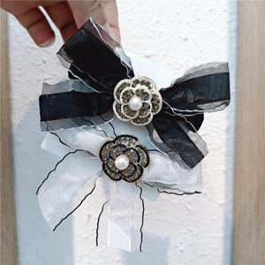 Detailed macro view of camellia flower hair clip with rhinestones and organza bow