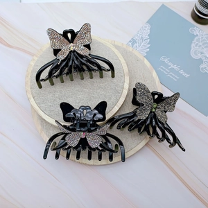Close-up of black acrylic butterfly hair claws with inlaid colorful rhinestones on wood
