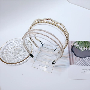 Detailed view of three pearl headbands set on a glass tray with elegant floral card