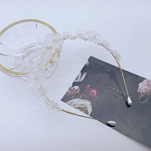 Détail d'un serre-tête doré avec fleurs blanches mates, perles et perles de cristal
