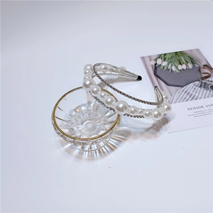 Close-up of double-layered headband featuring glossy white pearls and sparkling rhinestones