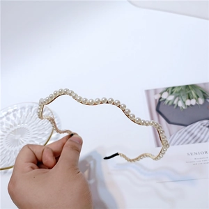 Detail of wavy metal headband with white faux pearls and black anti-slip end caps
