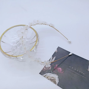 Détail d'un serre-tête fait main avec fleurs blanches givrées et perles