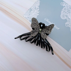 Detail of butterfly hair claw clip with black rhinestones and green gemstones