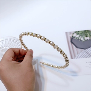 Detail of white pearl and rhinestone headband with gold alloy base and chic design