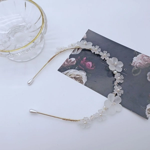 Détail du serre-tête floral blanc avec pétales mats et perles sur monture dorée