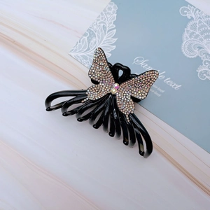 Macro detail of butterfly hair claw with multi-color rhinestones on black resin base