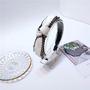 Detailed macro view of the cream-white fabric headband with black lace edge trim