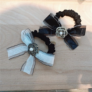 Detailed view of lace bow hair ties with rhinestone camellia and faux pearl center