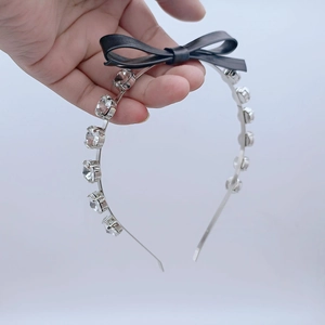Détail du serre-tête argenté avec strass brillants et un nœud en cuir noir