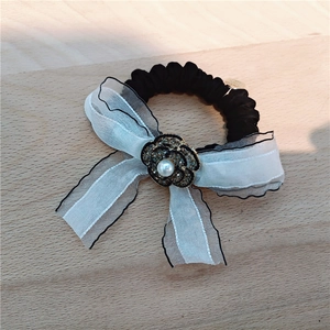 Detail of elegant white organza bow hair tie with camellia rhinestone and pearl charm