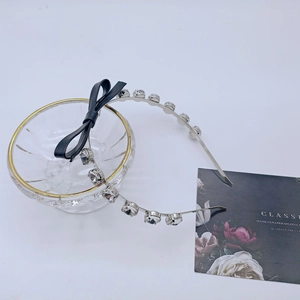 Détail d'un serre-tête en métal argenté avec des strass étincelants et un nœud en cuir noir