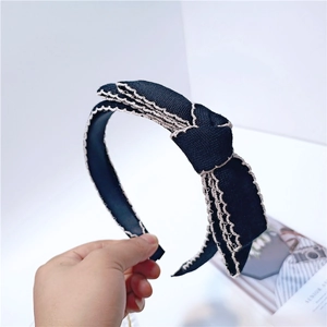 Elegant black knit headband with white lace trim and large bow held in hand