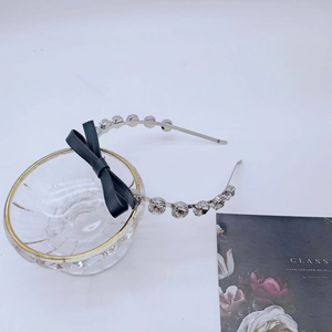 Détail d'un serre-tête argenté avec des strass brillants et un nœud noir élégant