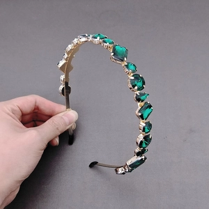 Detailed view of luxurious gold headband featuring vintage green crystal gemstones