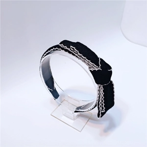 Close-up of black and white bow headband with textured knit fabric and wavy silver edges