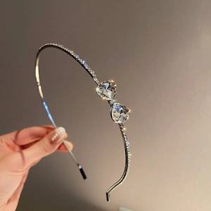 Detailed close-up of a silver headband featuring heart-shaped crystals and micro-pavé rhinestones