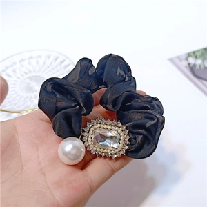 Close-up of elegant black chiffon hair scrunchie with sparkling crystals and large pearl detail
