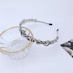 Close-up of luxury silver headband with shimmering crystals resting on a glass bowl