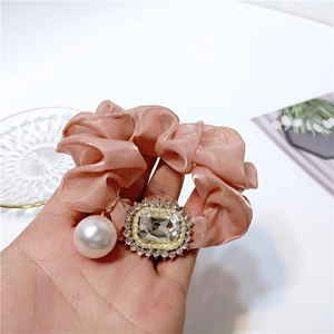 Detail of elegant satin hair scrunchie with sparkling cubic zirconia and pearl pendant
