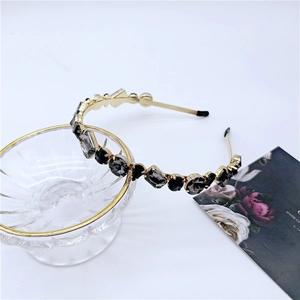 Detailed macro of a gold headband with faceted black crystals on a glass bowl