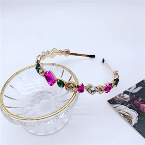 Detail of luxury headband with colorful crystals on a gold metal frame over a glass bowl