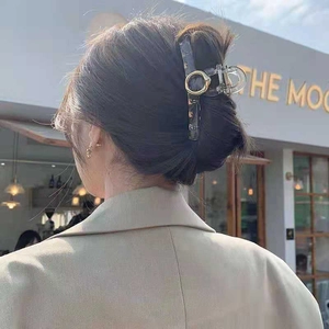 Dettaglio dell'elegante molletta per capelli in acrilico grigio scuro con anello d'oro