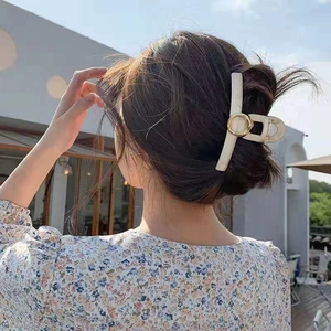 Dettaglio dell'elegante pinza per capelli in acrilico crema con anello d'oro sui capelli