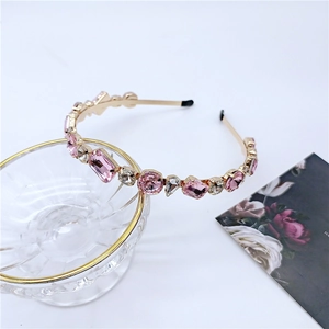Detail of luxury gold headband with pink and clear crystals on a glass bowl