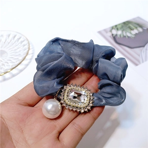 Detailed view of navy organza scrunchie with crystal centerpiece and pearl pendant
