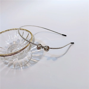 Close-up of thin silver rhinestone headband with crystal heart bow on glass bowl