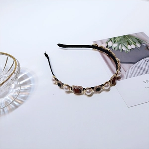 Close-up of Baroque pearl headband with square amber gems and crystals on black band