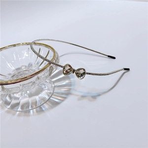 Close-up of slim silver headband with sparkling crystal heart bow and small rhinestones