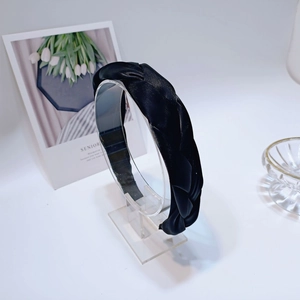 Dettaglio del cerchietto a treccia in raso nero lucido con elegante design a torsione