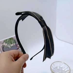 Close-up of black satin bow headband with sparkling rhinestone edges and elegant design