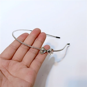 Detail of silver headband with rhinestone bow and double heart crystal accents