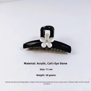 Détail d'une pince à cheveux noire de 11cm ornée d'une fleur en pierre œil de chat