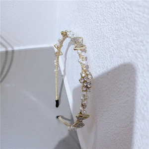 Macro detail of elegant golden headband featuring white pearls and rhinestone butterflies