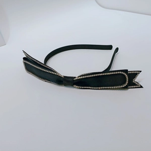 Close-up of black satin bow headband featuring dense sparkling rhinestone edges