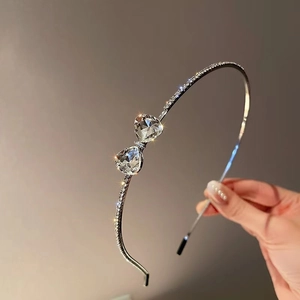 Elegant thin silver hairband featuring a sparkling rhinestone bow and crystal heart design