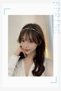 Close-up of golden headband with small cream flowers worn by a female model