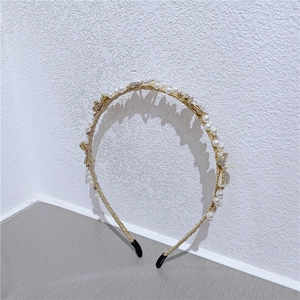 Detail of gold pearl headband with rhinestone butterfly accents on a white wall