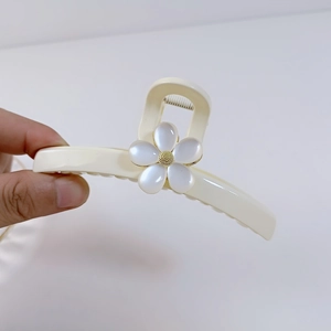 Détail d'une grande pince à cheveux crème avec une fleur blanche et un cœur doré