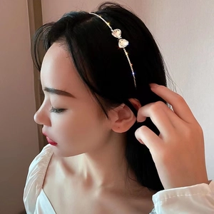 Elegant thin gold headband with double crystal heart accents worn by a model