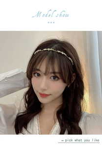Close-up of elegant gold metal headband with white floral and pearl embellishments