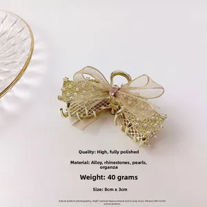 Détail de la pince à cheveux dorée avec nœud en organza, perles et strass taille 8cm