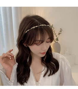 Detail of golden floral headband with white flowers and pearls on elegant model