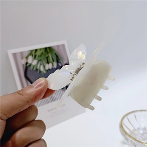 Detailed view of white pearlescent acetate butterfly hair claw clip with shell luster